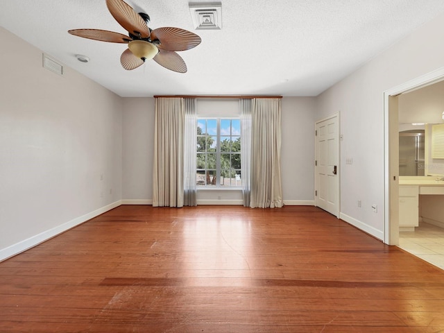 spare room with a textured ceiling, ceiling fan, and light wood-type flooring