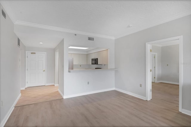 spare room with ornamental molding, a textured ceiling, and light wood-type flooring