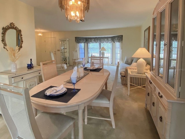 dining space with light carpet and a chandelier