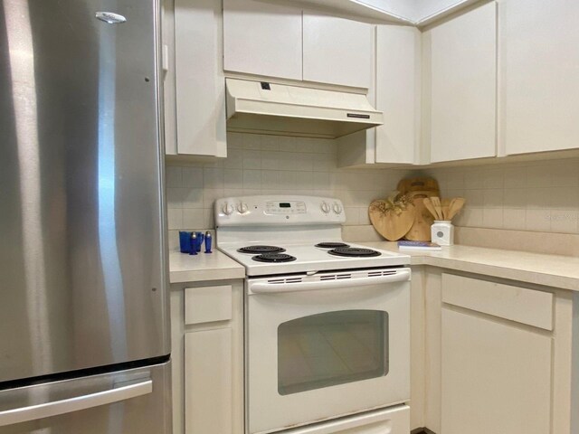 kitchen with backsplash, stainless steel refrigerator, white cabinetry, and white electric range oven