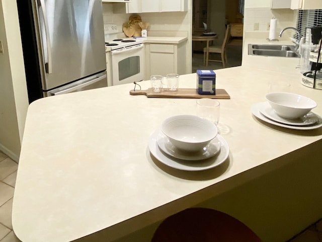 kitchen featuring stainless steel refrigerator, white range with electric cooktop, white cabinetry, and sink