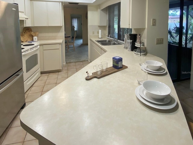 kitchen featuring stainless steel refrigerator, sink, tasteful backsplash, white electric stove, and white cabinets