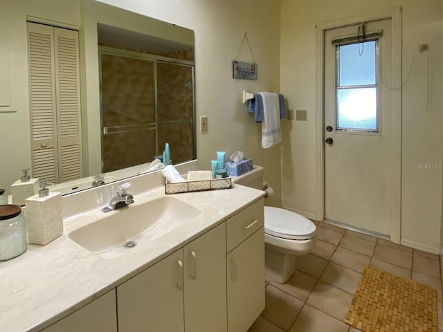 bathroom featuring tile patterned flooring, vanity, a shower with shower door, and toilet