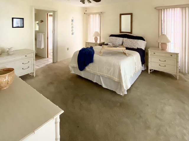 bedroom featuring ensuite bathroom, ceiling fan, light carpet, and multiple windows