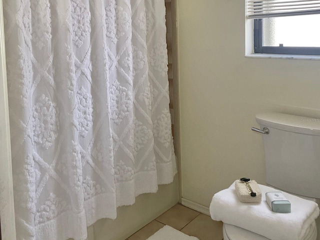 bathroom featuring toilet, tile patterned floors, and shower / bath combo with shower curtain