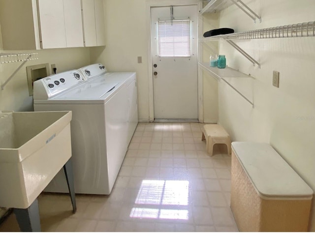 clothes washing area with washer and clothes dryer, cabinets, and sink