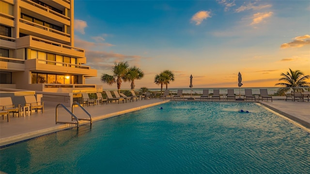 pool at dusk with a patio area