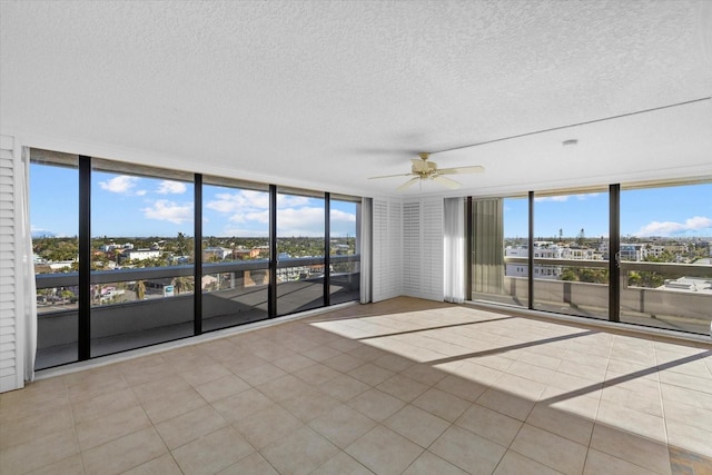 tiled empty room featuring ceiling fan, floor to ceiling windows, and a wealth of natural light