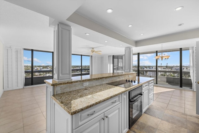 kitchen with white cabinets, hanging light fixtures, plenty of natural light, and black appliances