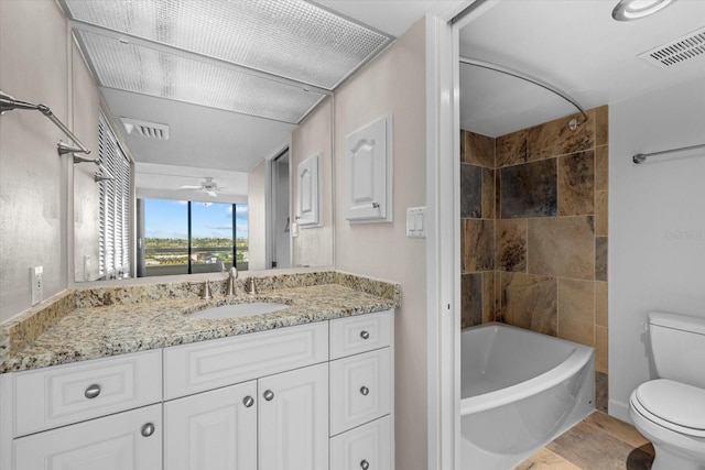 full bathroom featuring vanity, ceiling fan, toilet, and tiled shower / bath combo