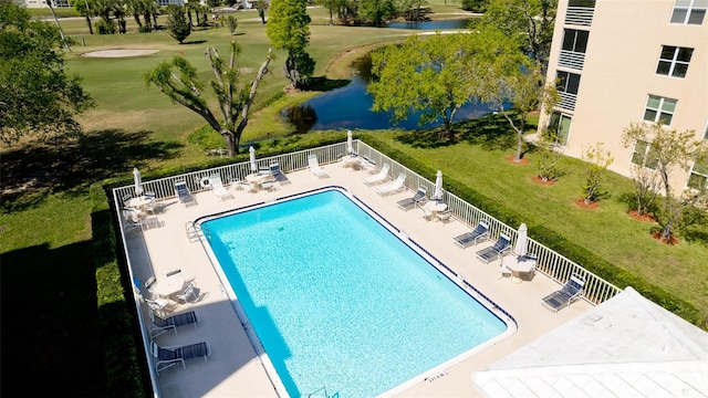 view of pool with a water view, a patio area, and a lawn