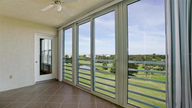 doorway to outside with ceiling fan, dark tile patterned flooring, and a textured ceiling