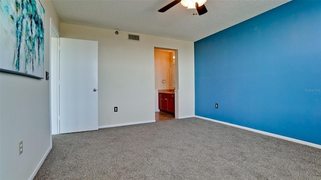 unfurnished bedroom with ceiling fan, ensuite bath, light carpet, and a textured ceiling