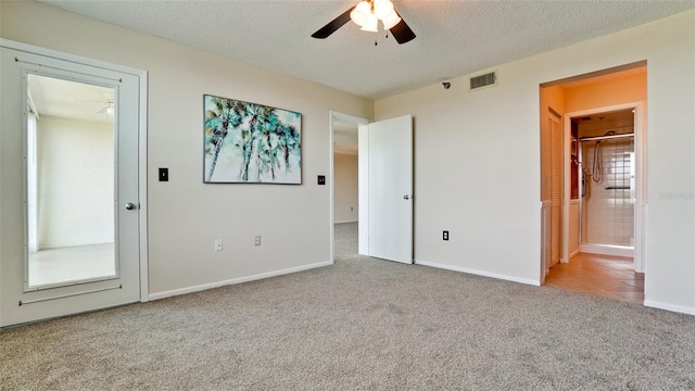 unfurnished bedroom featuring ceiling fan, light colored carpet, ensuite bathroom, and a textured ceiling