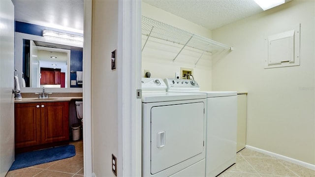 washroom featuring sink, light tile patterned floors, a textured ceiling, and washer and clothes dryer