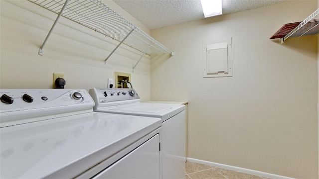 laundry area with washing machine and dryer, a textured ceiling, and light tile patterned floors