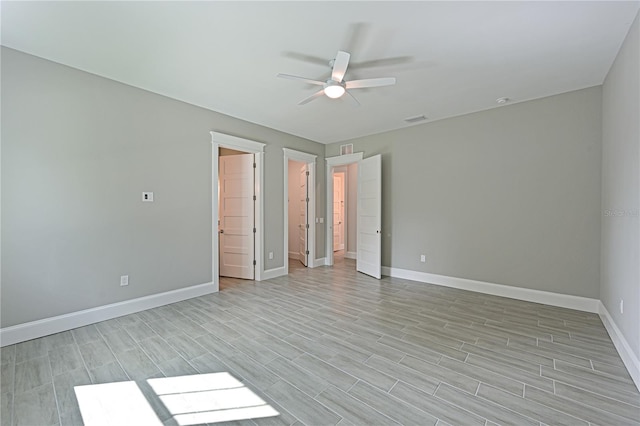 unfurnished bedroom with a walk in closet, a closet, ceiling fan, and light wood-type flooring