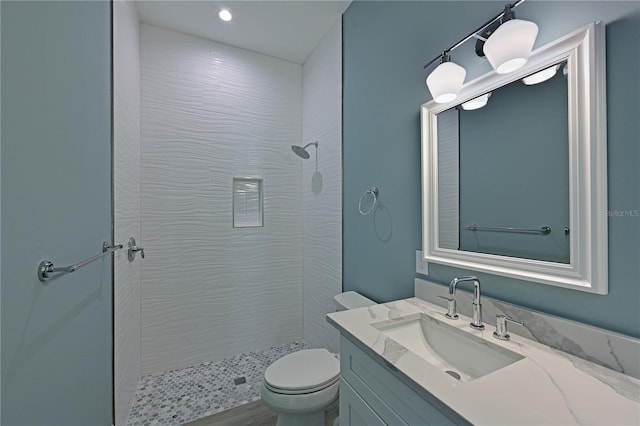 bathroom with vanity, toilet, and tiled shower