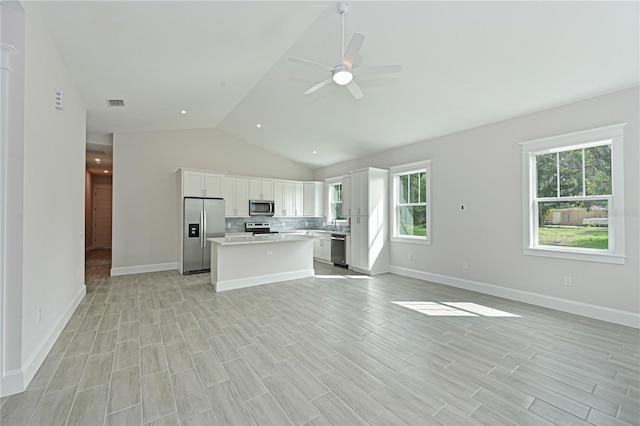 kitchen with stainless steel appliances, vaulted ceiling, ceiling fan, tasteful backsplash, and white cabinetry