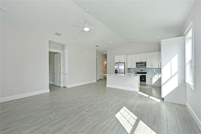 unfurnished living room with ceiling fan and vaulted ceiling