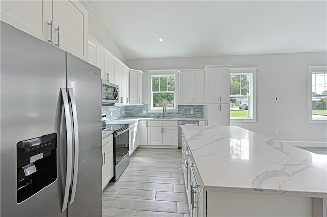 kitchen featuring white cabinets, light stone counters, tasteful backsplash, and stainless steel appliances