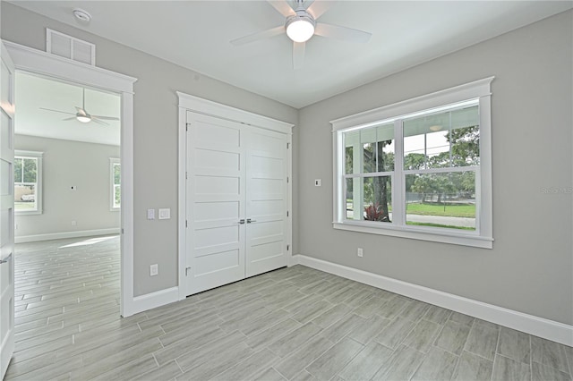 unfurnished bedroom with a closet, ceiling fan, and multiple windows