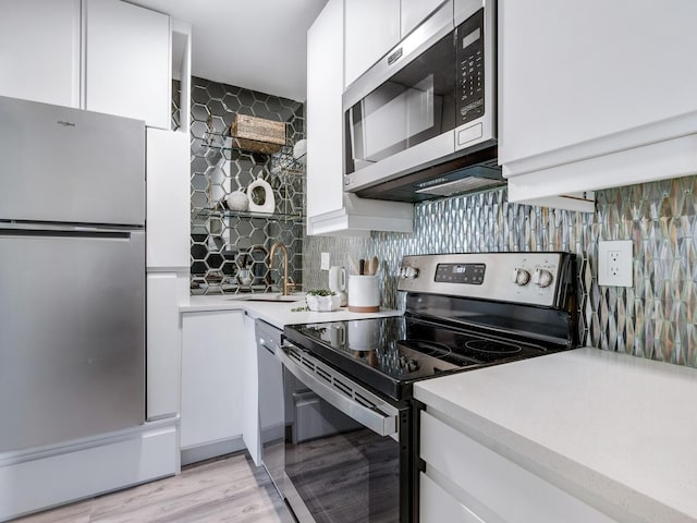 kitchen with white cabinetry, sink, tasteful backsplash, appliances with stainless steel finishes, and light wood-type flooring