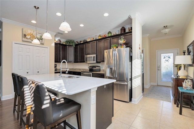 kitchen with ornamental molding, stainless steel appliances, sink, a breakfast bar, and a center island with sink