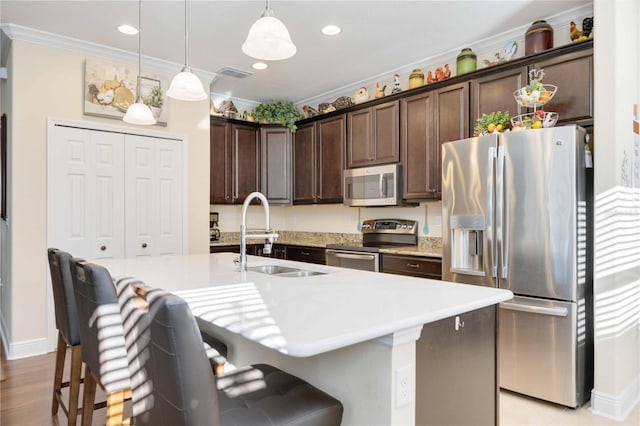 kitchen with an island with sink, a breakfast bar area, stainless steel appliances, and sink