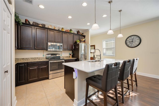 kitchen featuring crown molding, stainless steel appliances, sink, a kitchen bar, and a kitchen island with sink