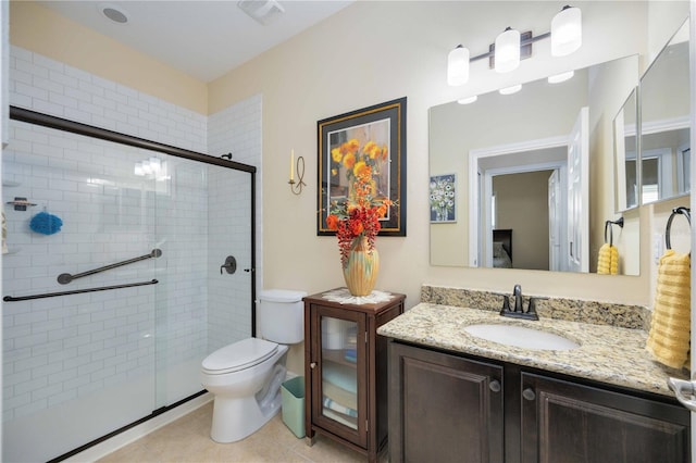 bathroom with a shower with door, vanity, toilet, and tile patterned floors