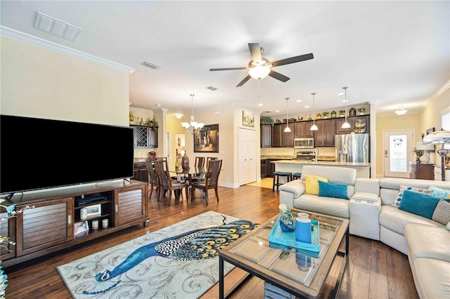 living room with dark wood-type flooring, ornamental molding, and ceiling fan with notable chandelier