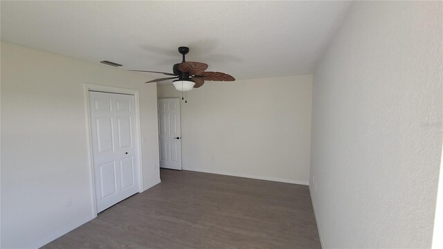 empty room with ceiling fan and dark wood-type flooring