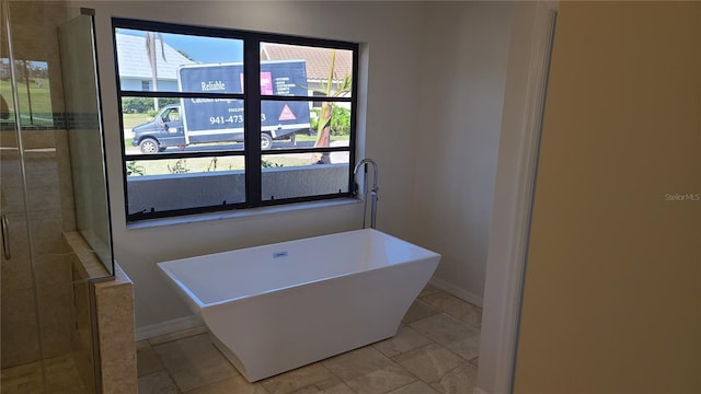 bathroom featuring a wealth of natural light, tile patterned floors, and a washtub