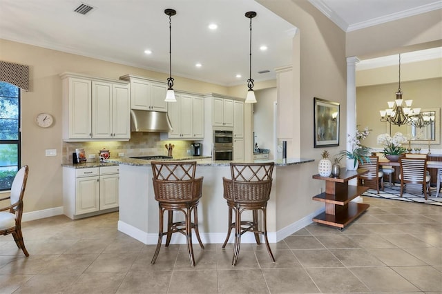 kitchen featuring light stone counters, decorative columns, kitchen peninsula, and stainless steel double oven