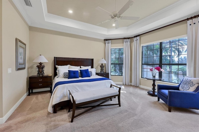 bedroom featuring light carpet, crown molding, a tray ceiling, and ceiling fan