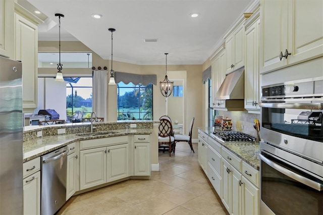 kitchen featuring light stone countertops, appliances with stainless steel finishes, hanging light fixtures, and cream cabinetry