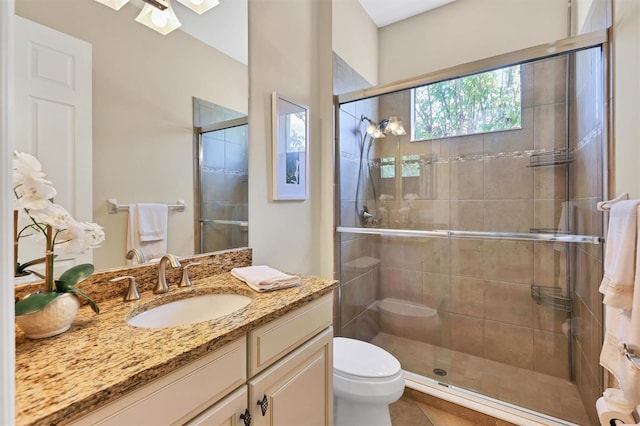 bathroom featuring toilet, a shower with shower door, vanity, and tile patterned floors