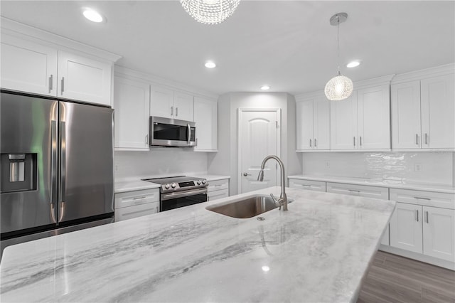 kitchen featuring tasteful backsplash, decorative light fixtures, sink, white cabinetry, and appliances with stainless steel finishes