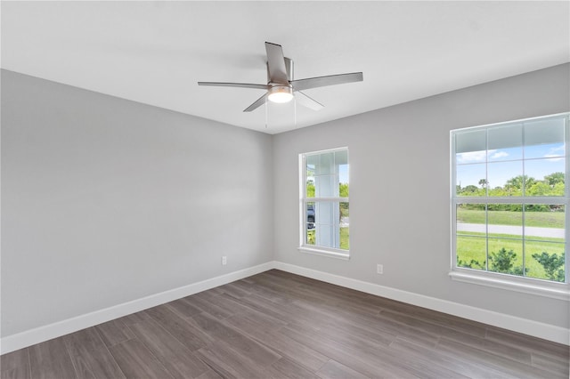 unfurnished room featuring a wealth of natural light, ceiling fan, and dark hardwood / wood-style flooring