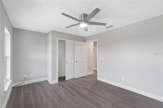 unfurnished bedroom with dark hardwood / wood-style flooring, a closet, and ceiling fan