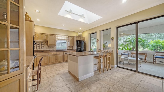 kitchen featuring a skylight, tasteful backsplash, black fridge with ice dispenser, a breakfast bar area, and light tile patterned flooring