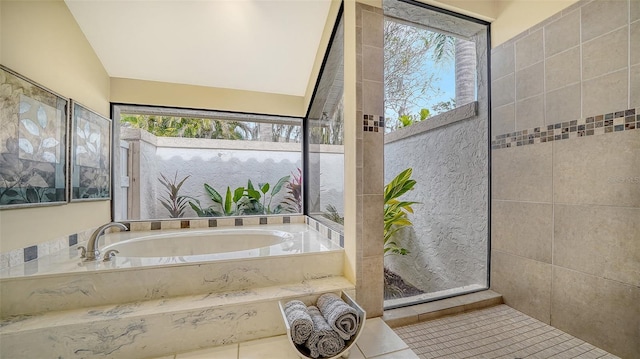 bathroom with tile patterned floors, tiled bath, plenty of natural light, and lofted ceiling