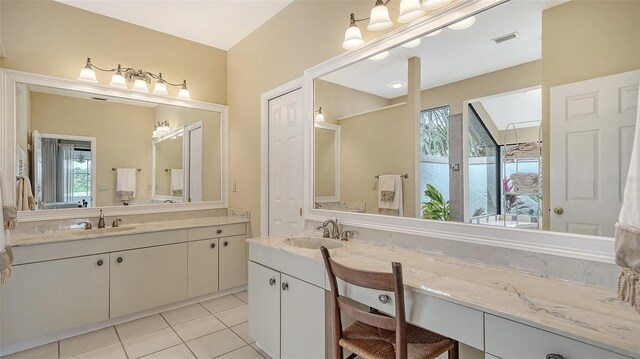 bathroom with tile patterned flooring, vanity, and a healthy amount of sunlight