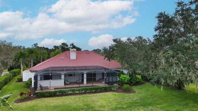 back of property featuring a lanai and a lawn