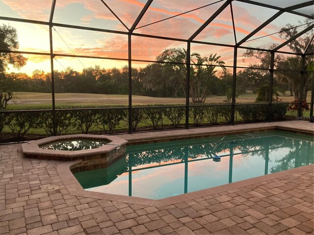 pool at dusk with a lanai and a patio area