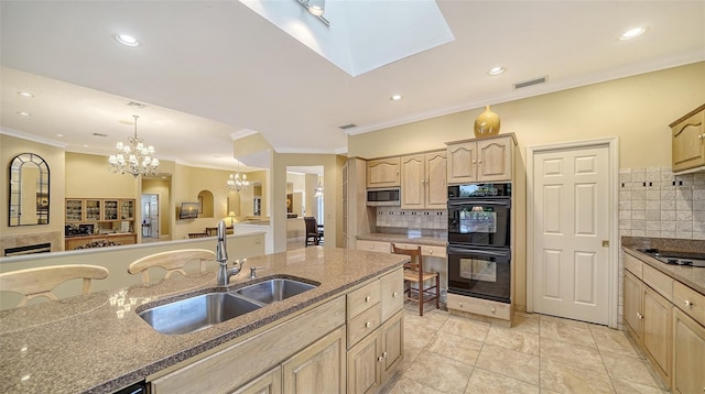 kitchen with backsplash, a skylight, sink, black appliances, and light brown cabinets