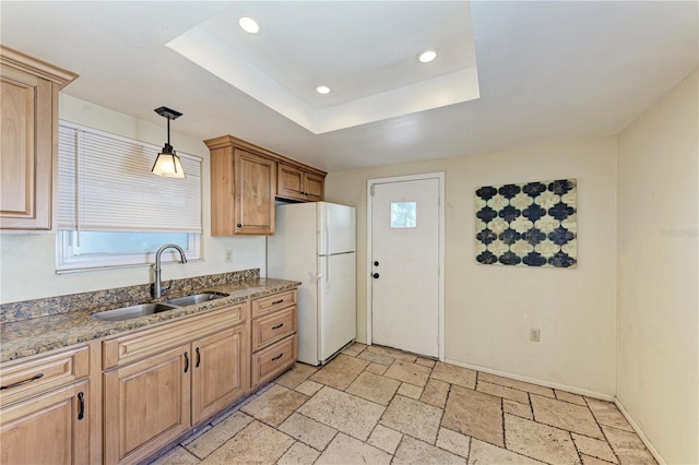 kitchen with white refrigerator, light tile flooring, hanging light fixtures, a raised ceiling, and sink