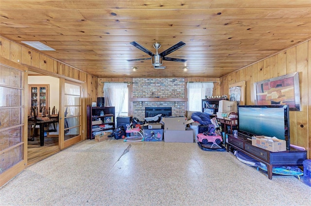 interior space with wooden walls, ceiling fan, wooden ceiling, and a fireplace