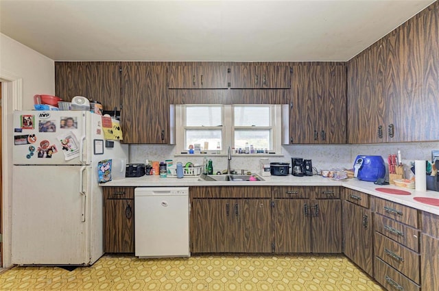 kitchen featuring dark brown cabinets, white appliances, and sink